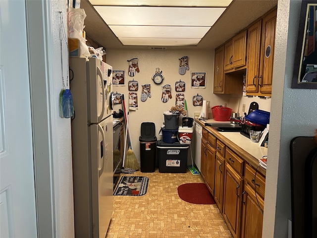 kitchen featuring light tile flooring, sink, white refrigerator, and dishwasher