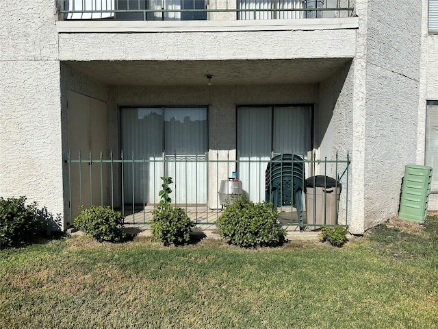 property entrance featuring a balcony and a yard