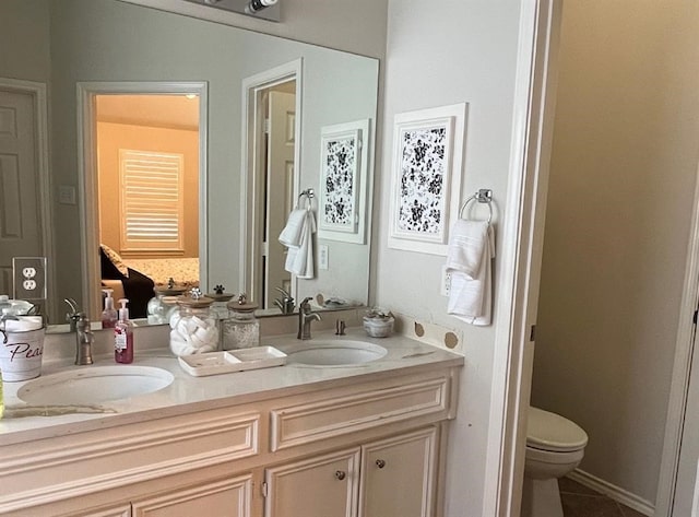 bathroom with toilet, dual sinks, and vanity with extensive cabinet space