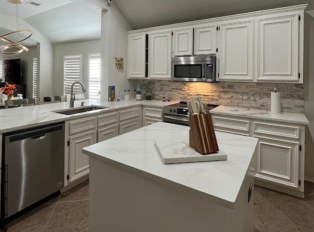 kitchen with kitchen peninsula, decorative light fixtures, an inviting chandelier, appliances with stainless steel finishes, and dark tile floors