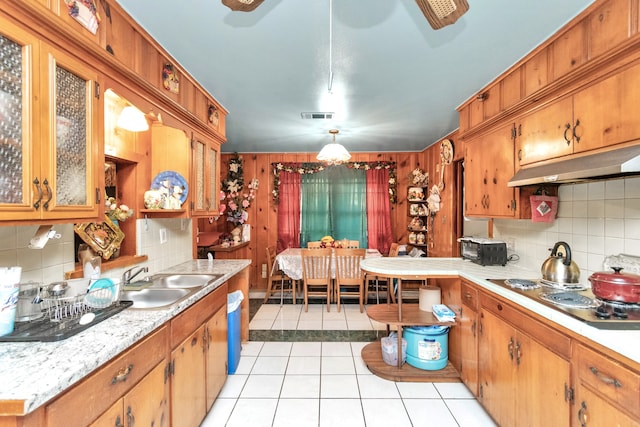 kitchen featuring sink, light tile floors, hanging light fixtures, electric cooktop, and backsplash