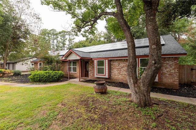 ranch-style home with a front yard and solar panels