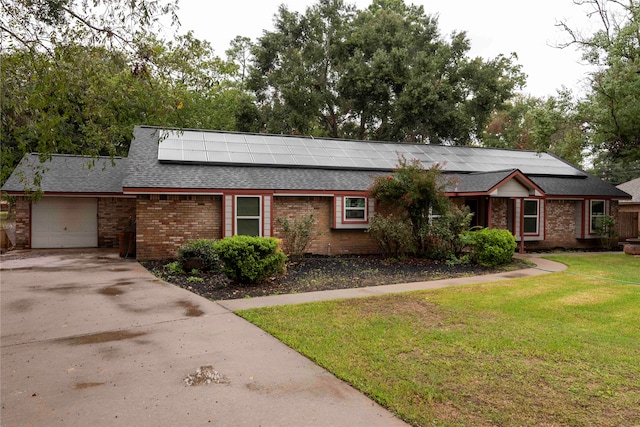 ranch-style home with solar panels, a front yard, and a garage