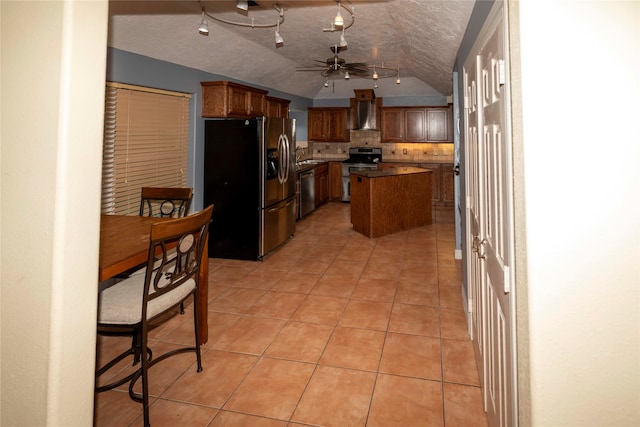 kitchen featuring ceiling fan, appliances with stainless steel finishes, backsplash, wall chimney exhaust hood, and a center island