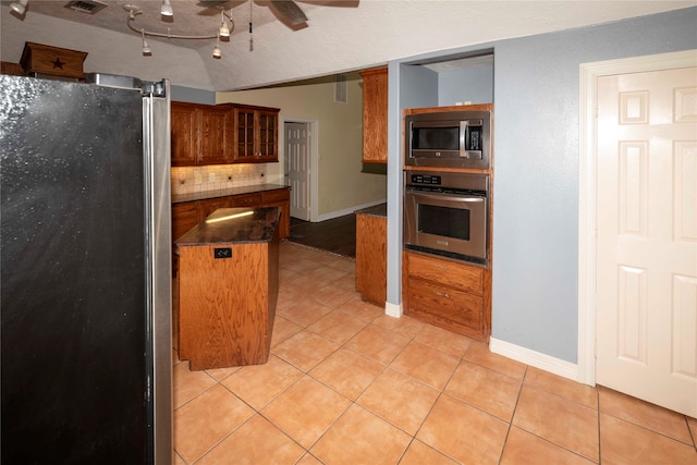 kitchen with backsplash, light tile flooring, stainless steel appliances, and ceiling fan