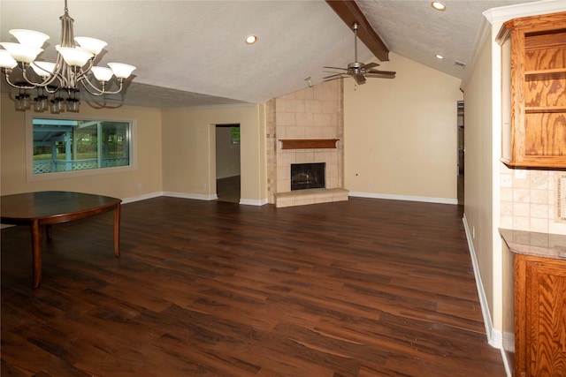 unfurnished living room with a tile fireplace, lofted ceiling with beams, dark wood-type flooring, a textured ceiling, and ceiling fan with notable chandelier