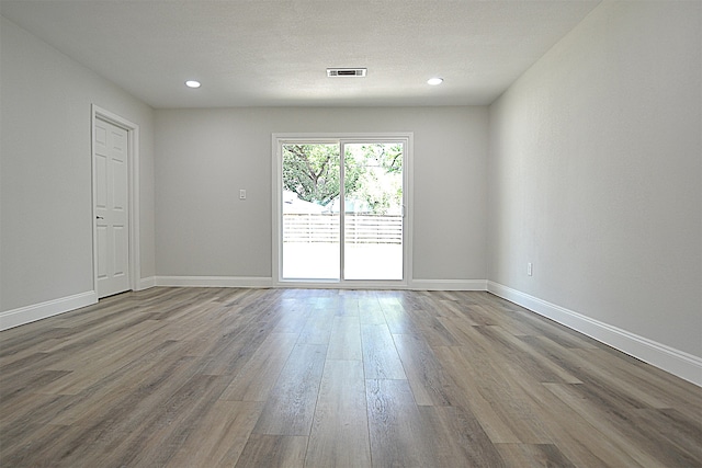 empty room with a textured ceiling and wood-type flooring