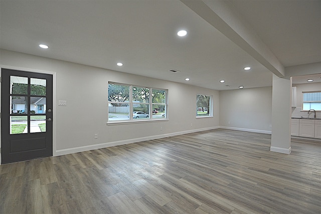 unfurnished living room featuring sink, plenty of natural light, and light wood-type flooring