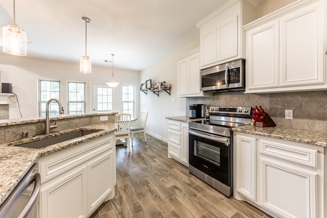 kitchen featuring sink, stainless steel appliances, white cabinets, hardwood / wood-style flooring, and pendant lighting