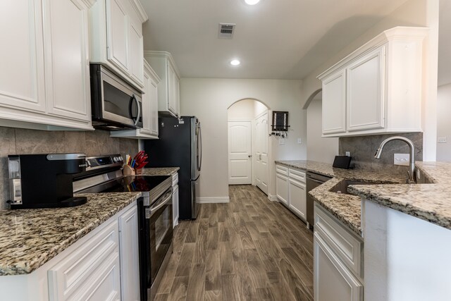 kitchen featuring backsplash, white cabinetry, dark wood-type flooring, and stainless steel appliances