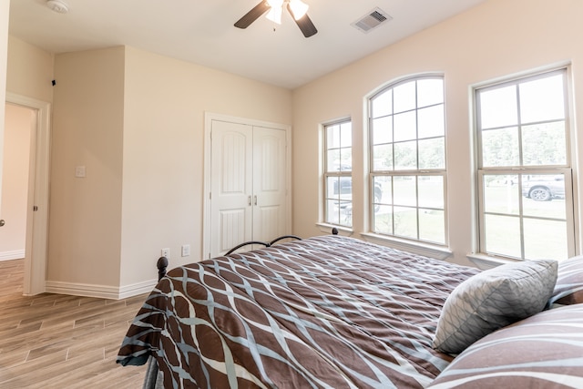 bedroom featuring a closet, multiple windows, light hardwood / wood-style floors, and ceiling fan