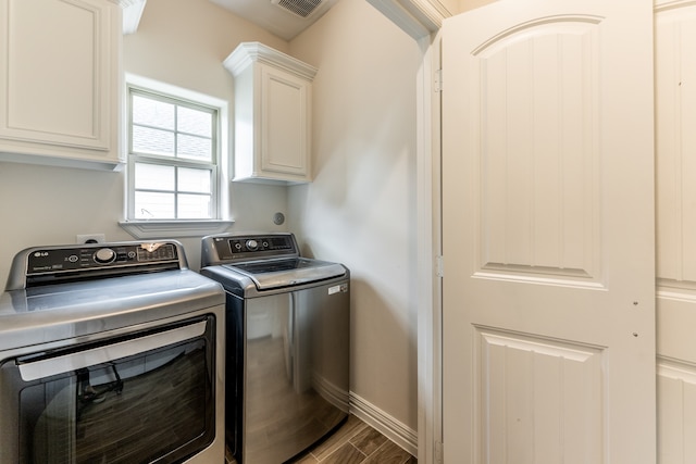 clothes washing area with washer and clothes dryer, cabinets, and dark wood-type flooring