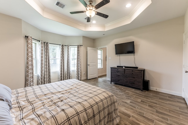 bedroom with ceiling fan, crown molding, a raised ceiling, and dark hardwood / wood-style flooring