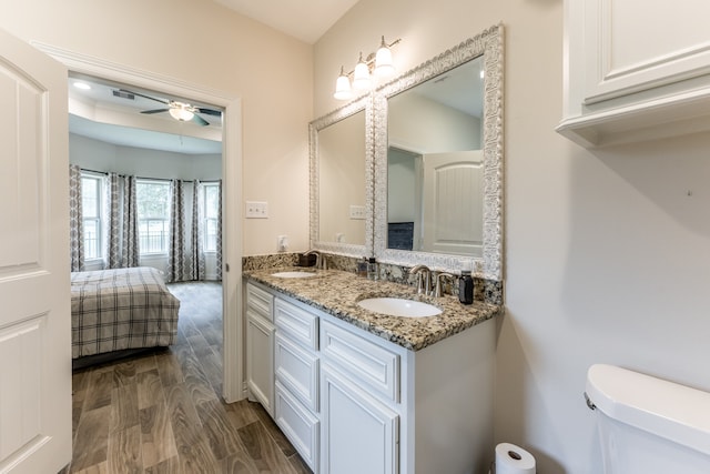 bathroom with oversized vanity, ceiling fan, toilet, wood-type flooring, and double sink