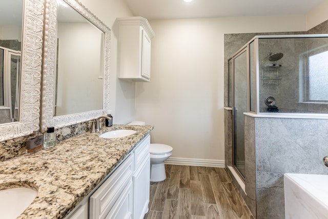 bathroom featuring double sink vanity, toilet, an enclosed shower, and wood-type flooring