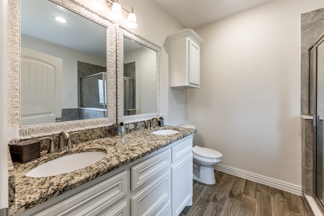 bathroom with toilet, an enclosed shower, hardwood / wood-style floors, dual sinks, and oversized vanity