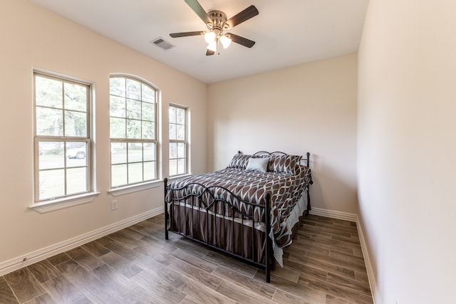 bedroom with multiple windows, ceiling fan, and wood-type flooring