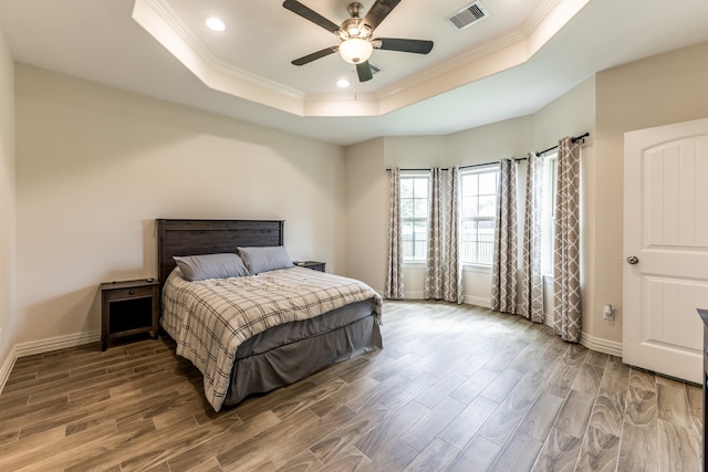 bedroom with ceiling fan, ornamental molding, a tray ceiling, and wood-type flooring