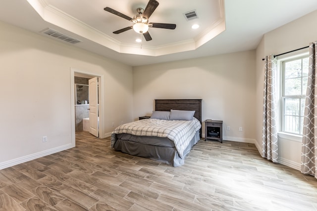 bedroom featuring ornamental molding, a raised ceiling, ensuite bath, and ceiling fan