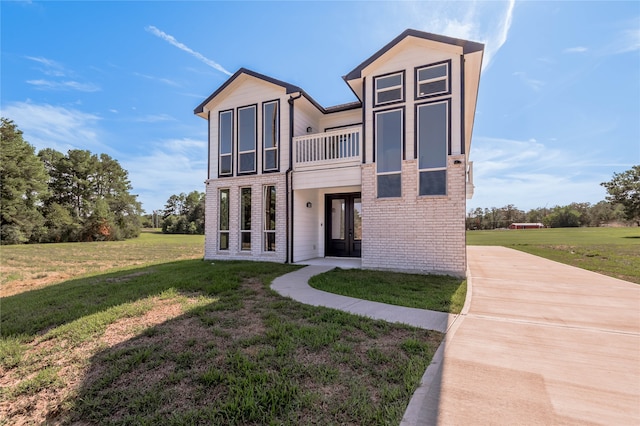 view of front of property featuring a front yard and a balcony