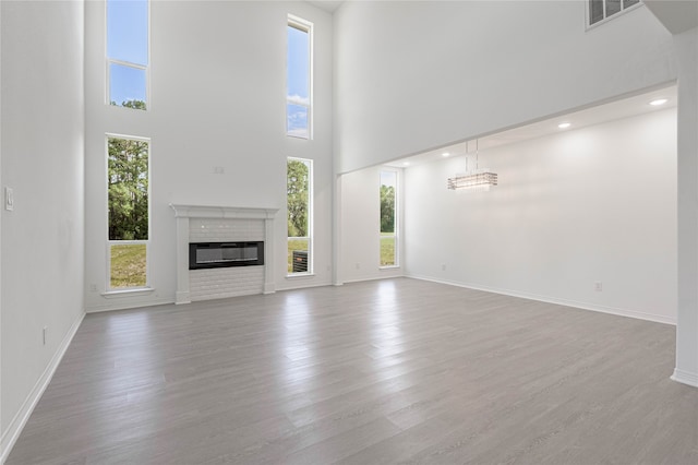 unfurnished living room featuring a chandelier, light hardwood / wood-style floors, and a high ceiling