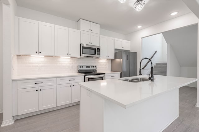 kitchen with backsplash, light hardwood / wood-style flooring, appliances with stainless steel finishes, and white cabinetry