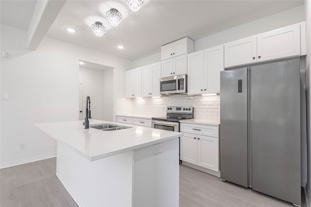 kitchen featuring appliances with stainless steel finishes, white cabinetry, light hardwood / wood-style flooring, a kitchen island with sink, and sink