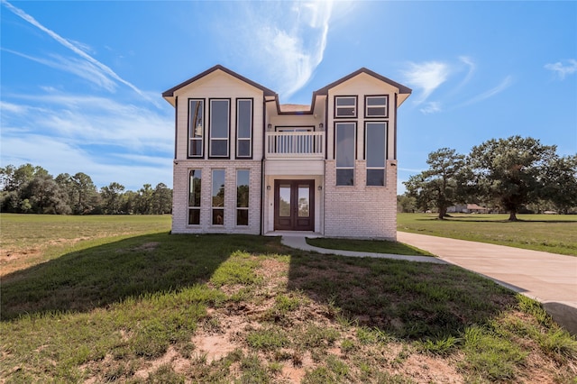 view of front of property with french doors, a front lawn, and a balcony