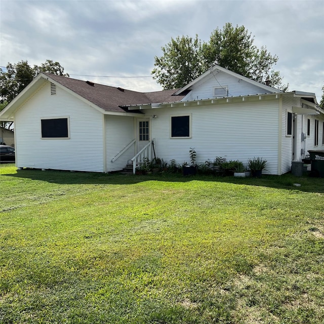 rear view of property featuring a lawn