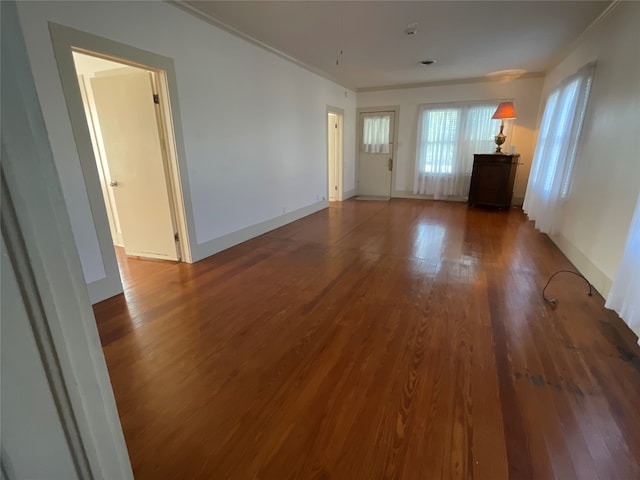 unfurnished living room featuring crown molding and dark wood-type flooring