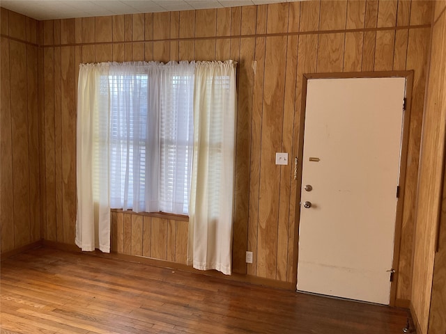 unfurnished room featuring light wood-type flooring and wooden walls
