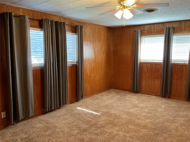 carpeted empty room featuring ceiling fan and wooden walls