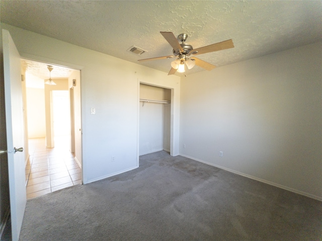 unfurnished bedroom featuring ceiling fan, a closet, dark colored carpet, and a textured ceiling