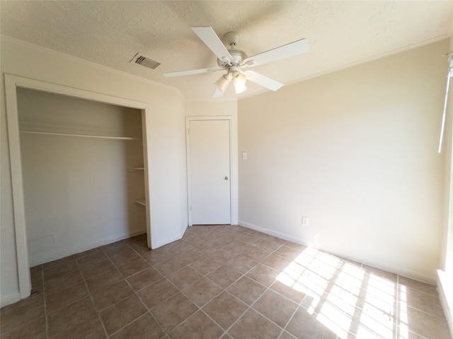 unfurnished bedroom with dark tile flooring, a closet, and ceiling fan