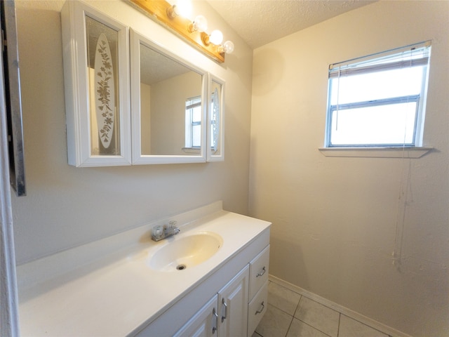 bathroom featuring a healthy amount of sunlight, large vanity, tile floors, and a textured ceiling