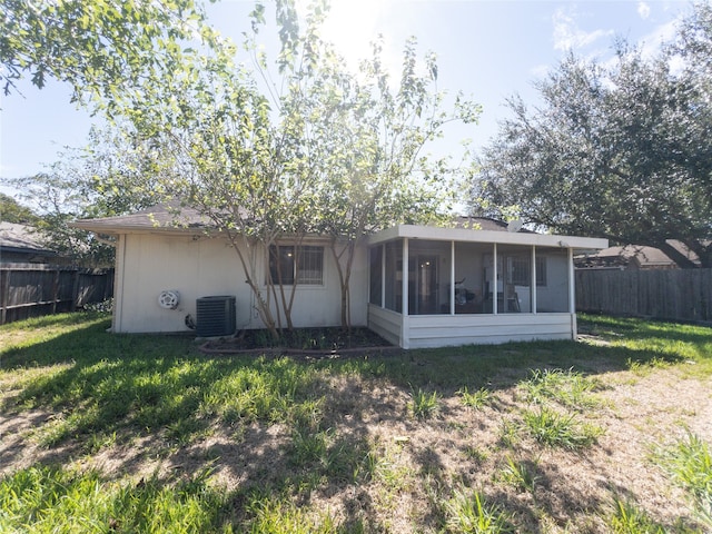 back of property featuring central air condition unit, a sunroom, and a yard