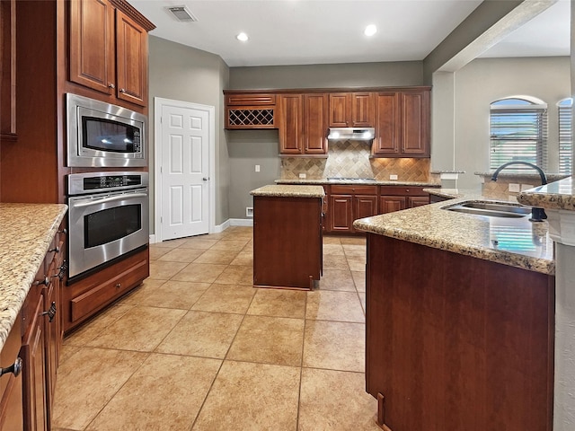 kitchen featuring sink, backsplash, a center island, light tile patterned floors, and stainless steel appliances