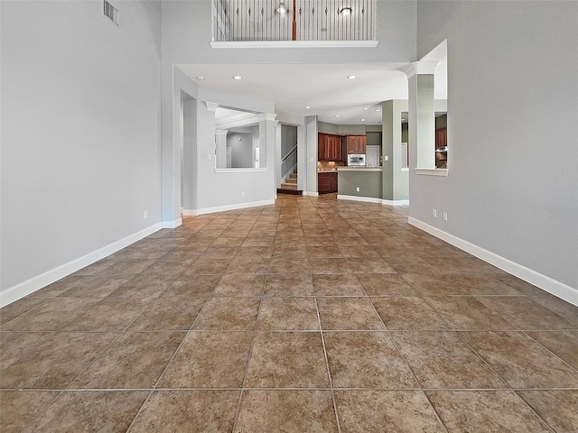 unfurnished living room with a towering ceiling and tile patterned floors