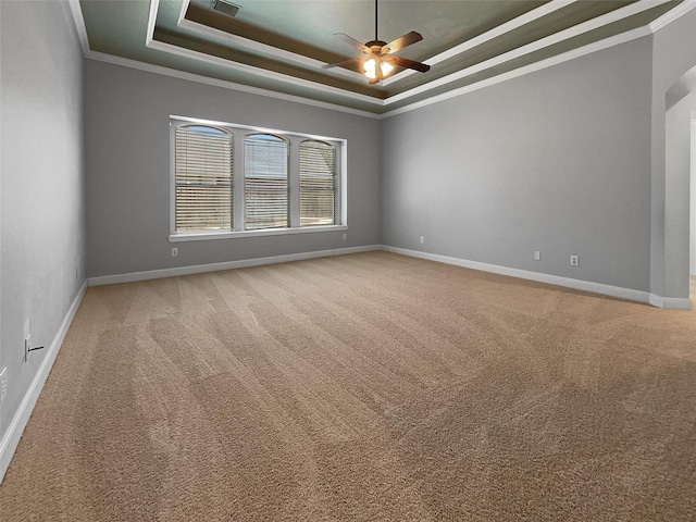 carpeted spare room featuring ceiling fan, ornamental molding, and a tray ceiling