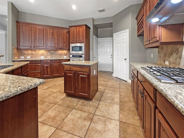 kitchen with sink, light stone countertops, exhaust hood, and appliances with stainless steel finishes