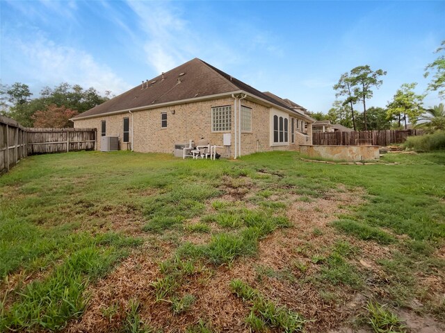 back of property featuring cooling unit and a lawn