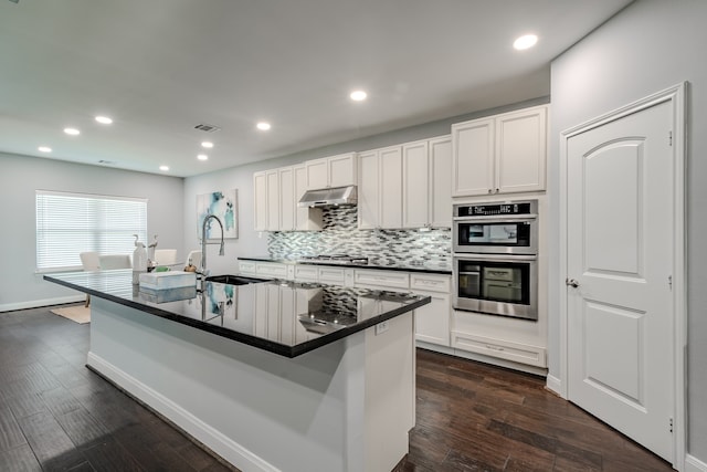 kitchen with a kitchen island with sink, white cabinets, dark hardwood / wood-style floors, and stainless steel appliances