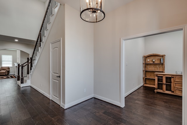 interior space with an inviting chandelier, a towering ceiling, and dark hardwood / wood-style flooring