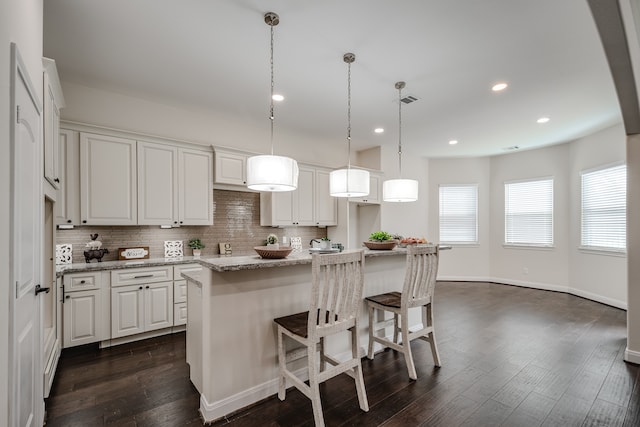 kitchen featuring pendant lighting, backsplash, dark wood-type flooring, and white cabinets