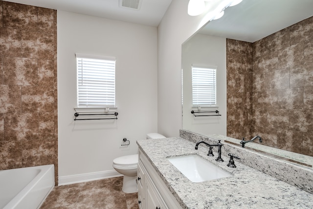 bathroom with toilet, tile floors, vanity with extensive cabinet space, and a wealth of natural light