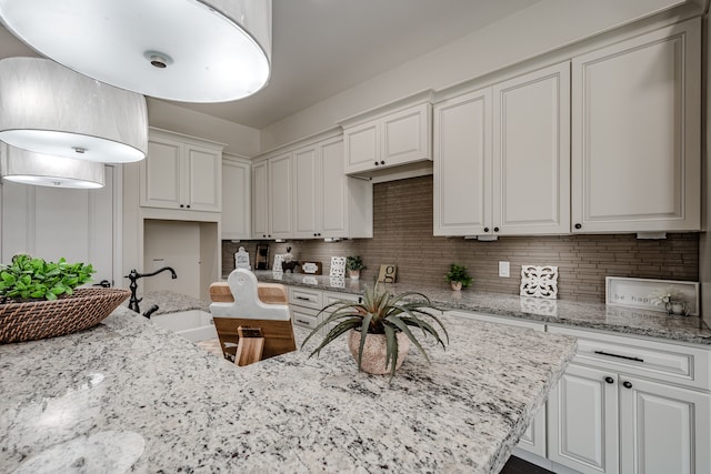 kitchen with white cabinetry and light stone counters