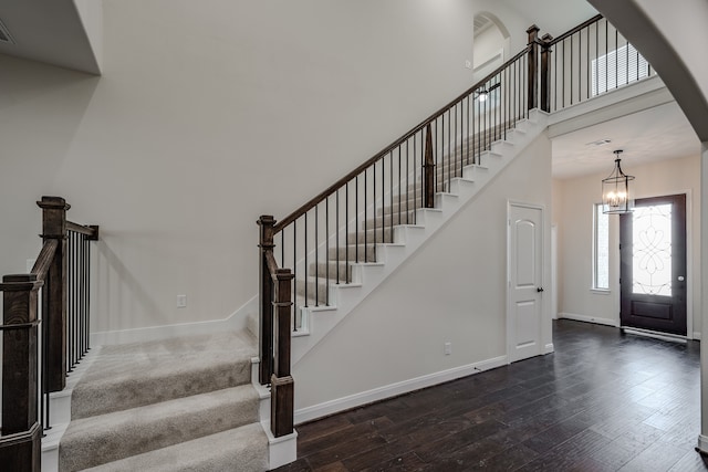 entrance foyer with an inviting chandelier, dark wood-type flooring, and a towering ceiling