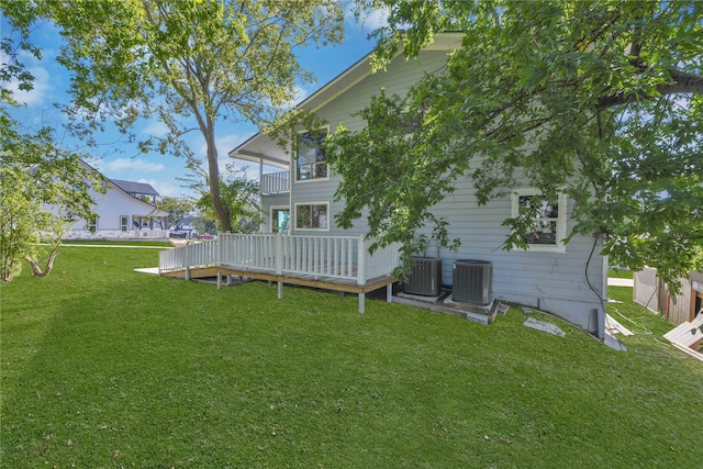 rear view of property with a wooden deck, central AC unit, and a yard