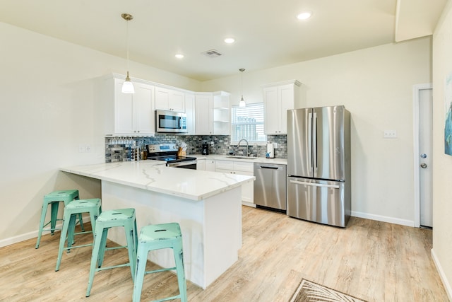 kitchen featuring white cabinets, appliances with stainless steel finishes, decorative light fixtures, and light stone countertops