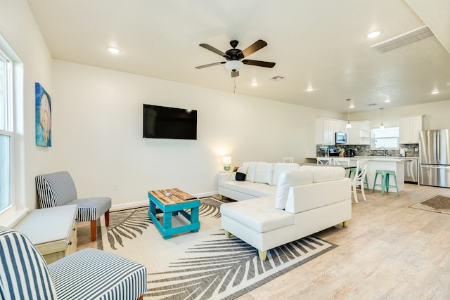 living room featuring ceiling fan, sink, and light wood-type flooring